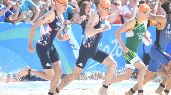Group of athletes running towards the sea, ready to start a swimming race