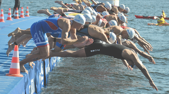 Group of swimmers diving in the sea, ready to start a swimming race